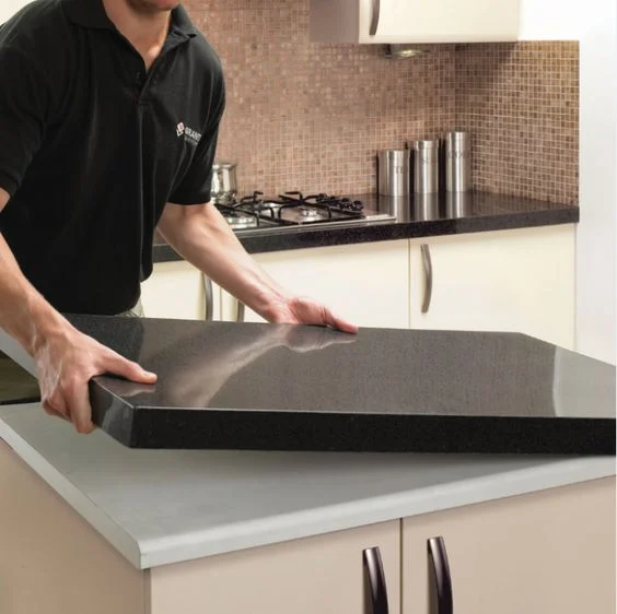 Un profesional instalando encimeras de cocina, manipulando una pieza de granito en una cocina moderna.