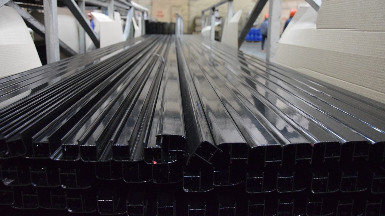 Black aluminum window frames neatly stacked in a manufacturing warehouse.