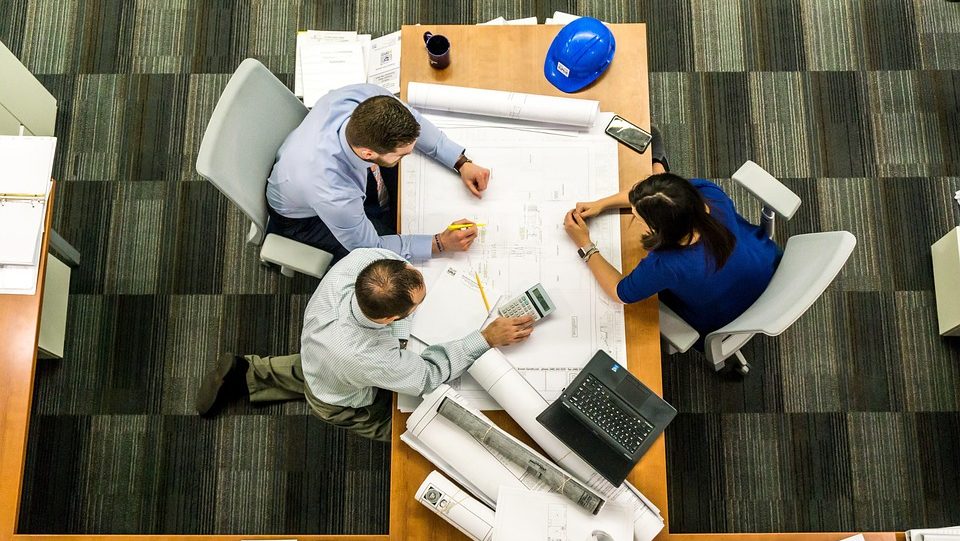 A team of designers and builders collaborating over project blueprints in a meeting room.