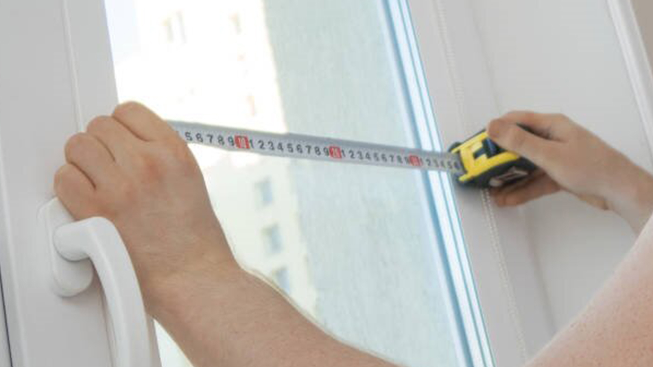 A homeowner measuring a window frame to ensure accurate dimensions before placing an order with a manufacturer.
