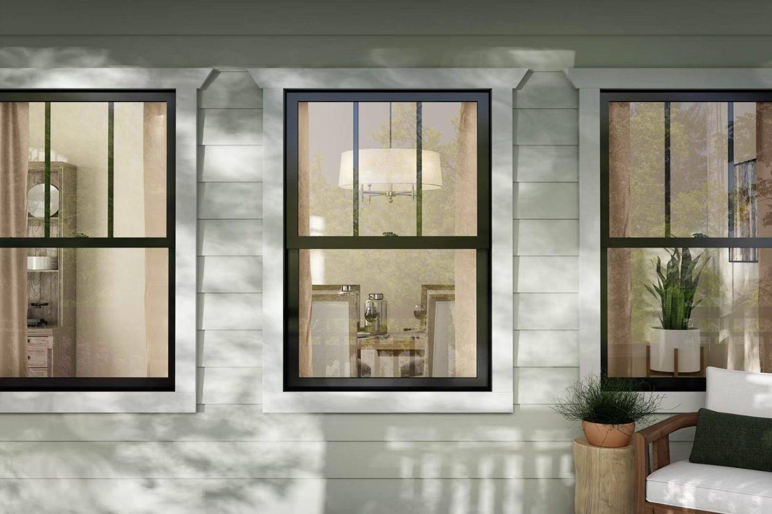 Modern black-framed residential aluminum windows on a light green house, reflecting warm interior lighting and outdoor greenery.