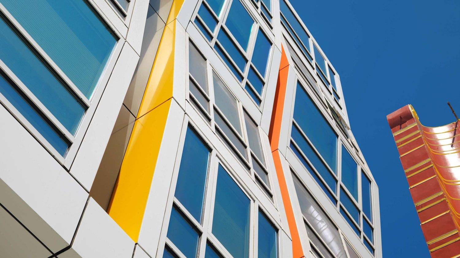 How to Choose the Best Commercial Replacement Windows: 2025 Guide for Architects 1 Modern midrise building with large aluminum windows and vibrant architectural design, blending commercial and residential spaces.