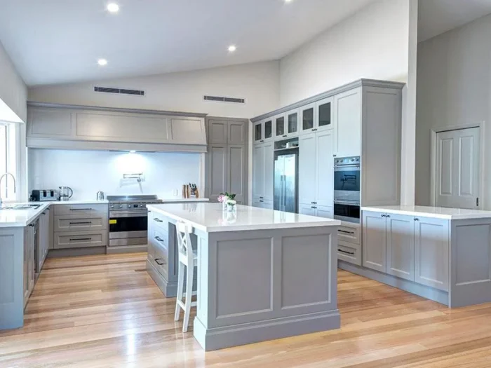 25 ideas inspiradoras de gabinetes de cocina en tonos greige para realzar tu hogar 5 Cocina de estilo costero con gabinetes color grisáceo, encimeras blancas y una isla espaciosa para un diseño moderno y aireado.