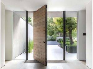 Luxury modern pivot entry door with a sleek wooden finish, surrounded by floor-to-ceiling glass panels, offering an elegant and contemporary aesthetic.