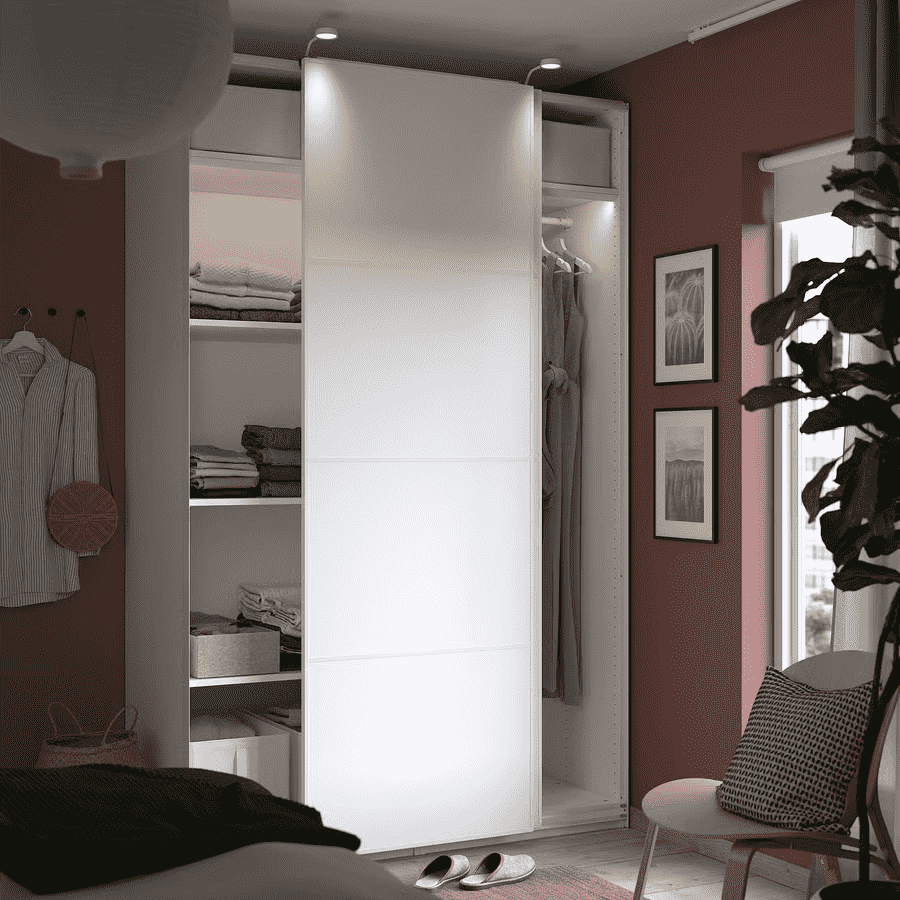 A slim, white IKEA wardrobe with sliding doors and internal shelving, ideal for compact spaces.