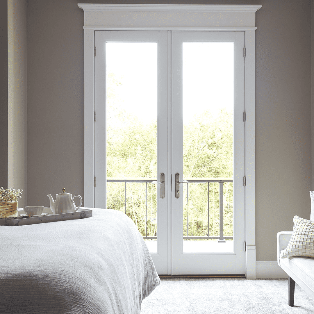 white french doors opening from bedroom to sunny balcony view