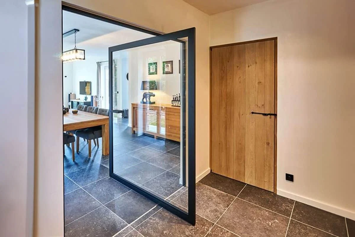 A luxury pivot aluminum door with a central hinge and minimalist vertical handle design.