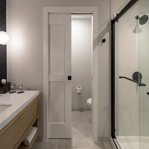 A minimalist pocket bathroom door disappearing into the wall to free space in a compact modern bathroom.